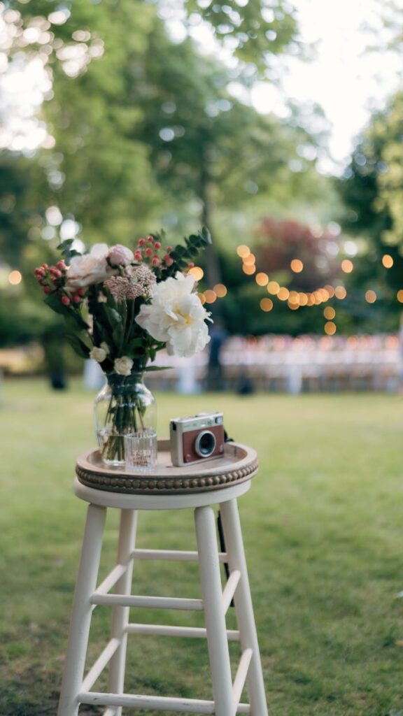 Meeleolu pilt ürituselt A charming bouquet and vintage camera on a stool in a garden setting, ideal for wedding themes.