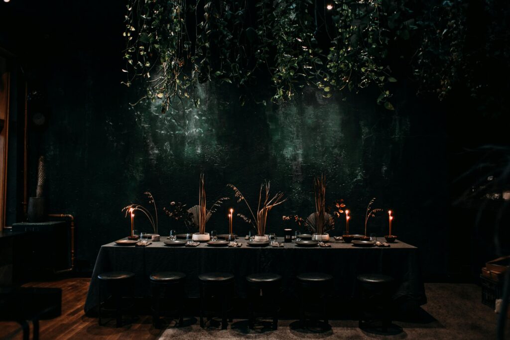 pexels-photo-4577179-4577179 Chic dining setup with candles and hanging plants, exuding a cozy ambiance.