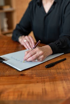pexels-photo-8871939-8871939 Professional woman writing on clipboard with a pen in a workplace setting.